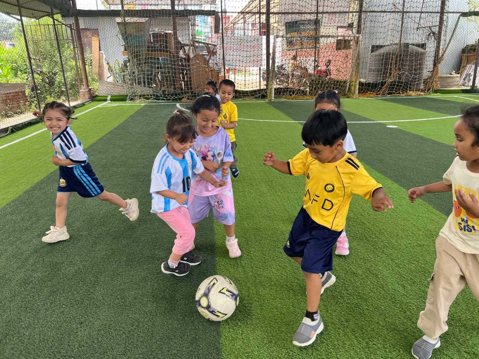 Young children chasing a football on the futsal pitch